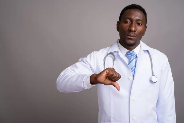 Young handsome African man doctor against gray background — Stock Photo, Image