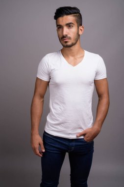 Genç yakışıklı Farsça adam gri bir arka plana dayanır
