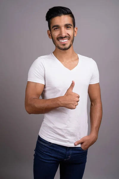 Junger gutaussehender persischer Mann mit grauem Hintergrund — Stockfoto