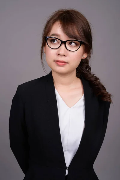 灰色の背景の眼鏡を身に着けている若い美しいアジア実業家のスタジオ撮影 — ストック写真
