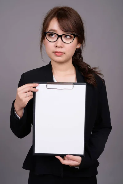 Beautiful Asian businesswoman showing copyspace in clipboard — Stock Photo, Image