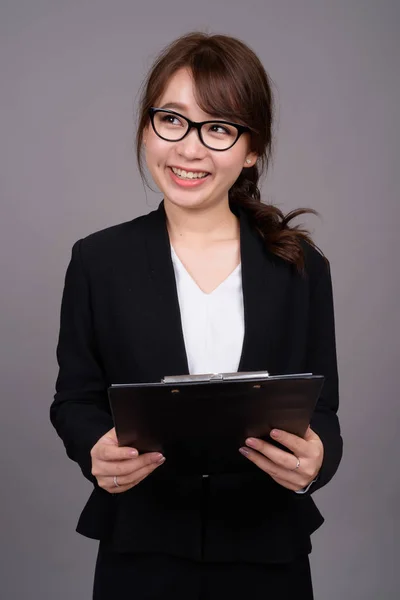 Joven hermosa mujer de negocios asiática contra fondo gris —  Fotos de Stock
