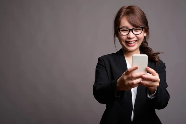 Young beautiful Asian businesswoman using mobile phone — Stock Photo, Image