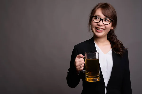 Молодая красивая азиатская бизнесвумен держит стакан пива — стоковое фото