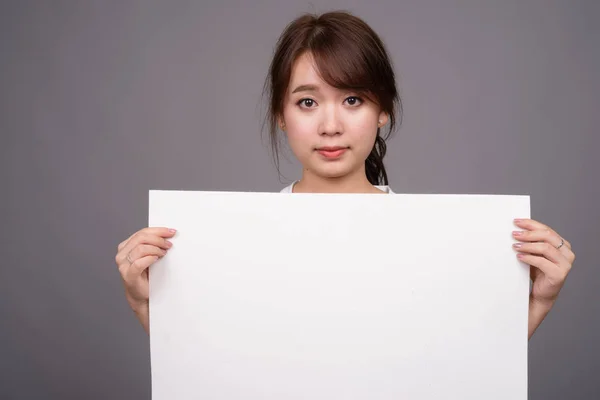 Mulher asiática mostrando placa branca vazia com copyspace — Fotografia de Stock