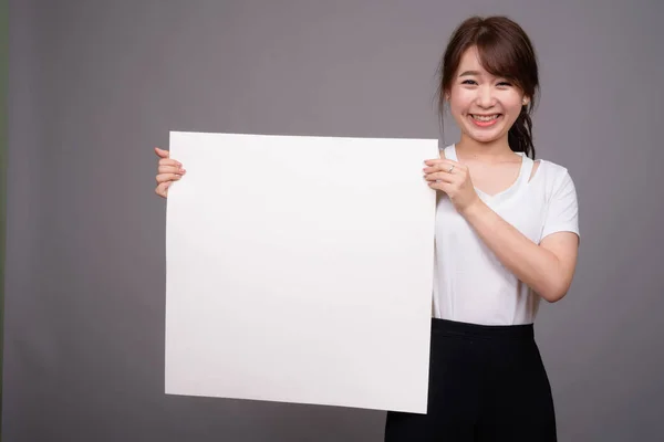 Mulher asiática mostrando placa branca vazia com copyspace — Fotografia de Stock