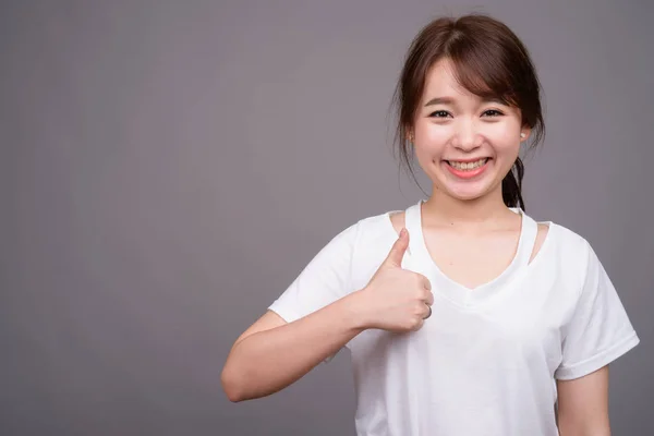 Joven hermosa mujer asiática contra fondo gris —  Fotos de Stock