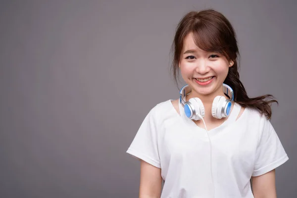 Jovem bela mulher asiática usando fones de ouvido para música — Fotografia de Stock