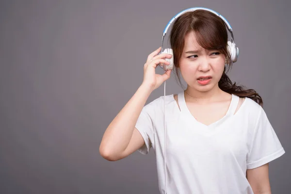 Jonge mooie Aziatische vrouw dragen hoofdtelefoon voor muziek — Stockfoto