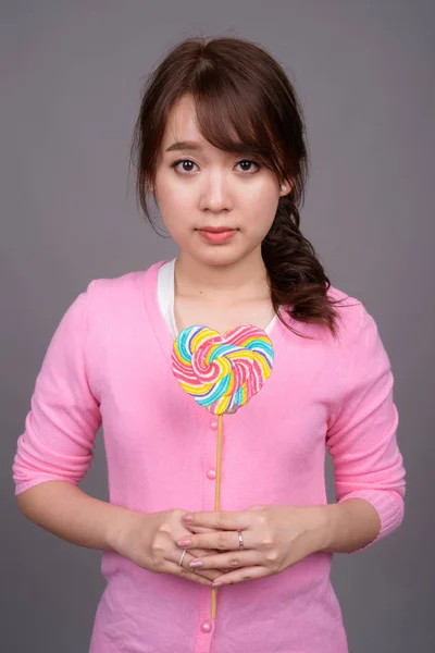 拿着五颜六色的棒棒糖的年轻美丽的亚洲女人 — 图库照片