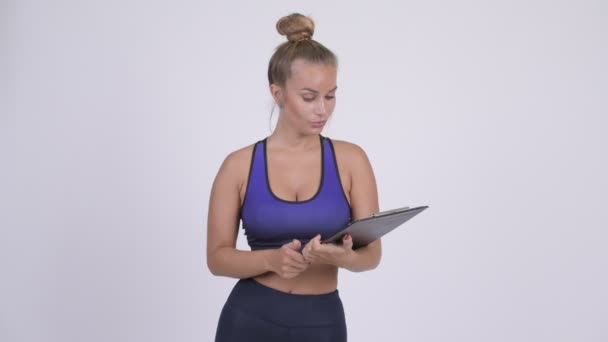 Счастливая молодая женщина инструктор физкультуры показывая планшет и показывая большие пальцы вверх — стоковое видео