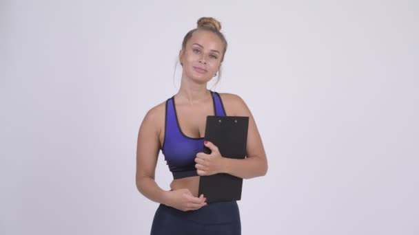 Joven hermosa mujer rubia como instructor de gimnasio con portapapeles — Vídeos de Stock
