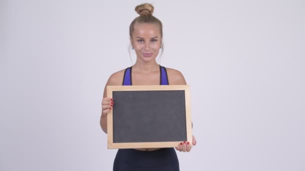 Happy young beautiful blonde woman holding blackboard — Stock Video
