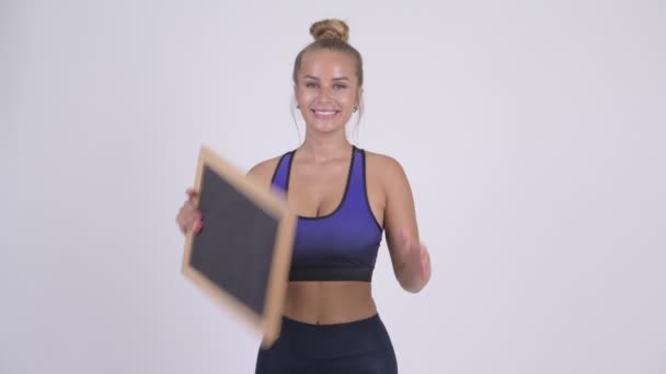 Happy young beautiful blonde woman holding blackboard — Stock Video