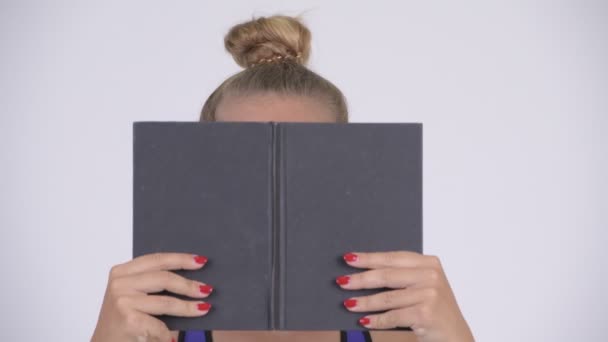 Молода красива блондинка прикриває обличчя книгою — стокове відео