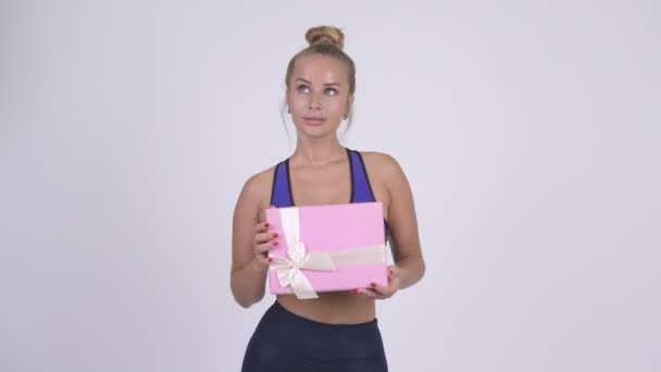 Glücklich junge schöne blonde Frau denken, während sie Geschenk-Box — Stockvideo
