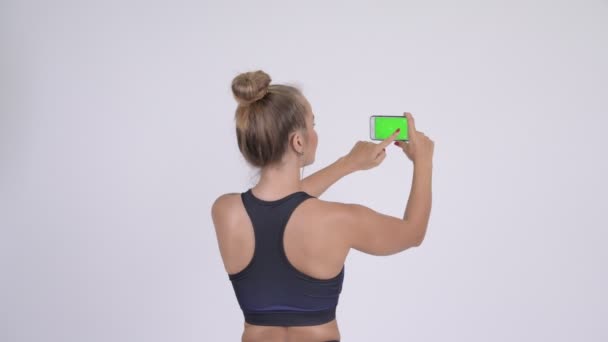 Вид сзади на молодую блондинку, фотографирующую с телефона — стоковое видео
