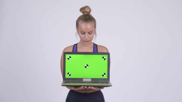 Happy young beautiful blonde woman thinking while showing laptop — Stock Video