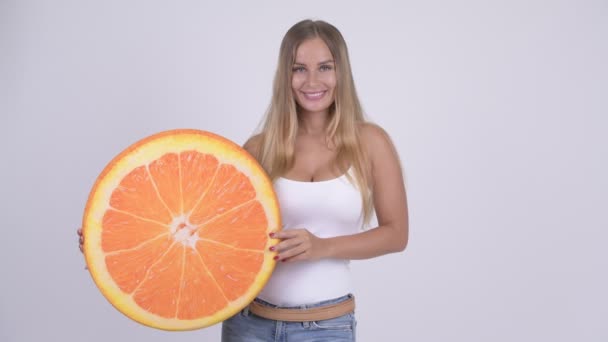 Happy young beautiful blonde woman with orange pillow as healthy concept — Stock Video
