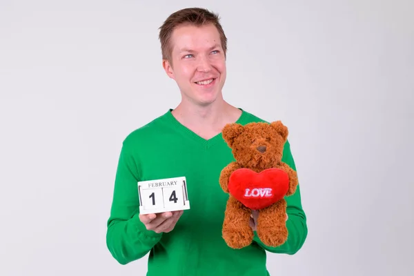 Happy young man thinking with calendar block and teddy bear for Valentines day — Stock Photo, Image