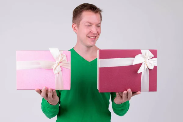 Счастливый молодой человек сравнивает две подарочные коробки, готовые к Дню Святого Валентина — стоковое фото