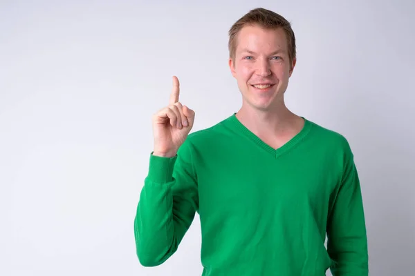 Jovem feliz bonito homem sorrindo enquanto apontando o dedo para cima — Fotografia de Stock