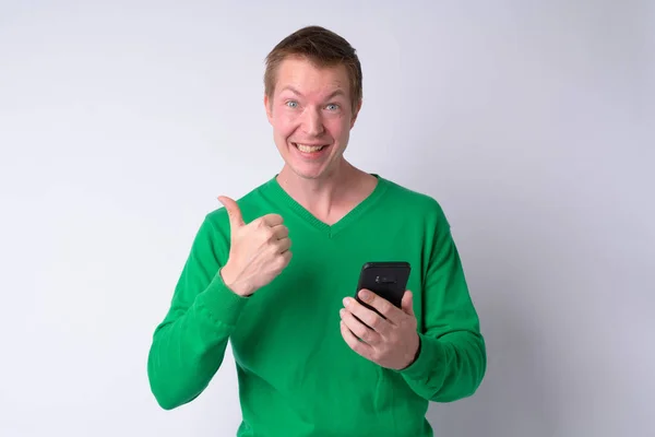 Happy young handsome man using phone and giving thumbs up — Stock Photo, Image