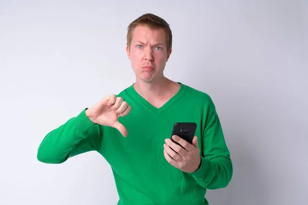 Portrait de jeune homme triste utilisant le téléphone et donnant pouces vers le bas — Photo