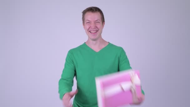 Happy young handsome man with gift box and giving thumbs up — Stock Video