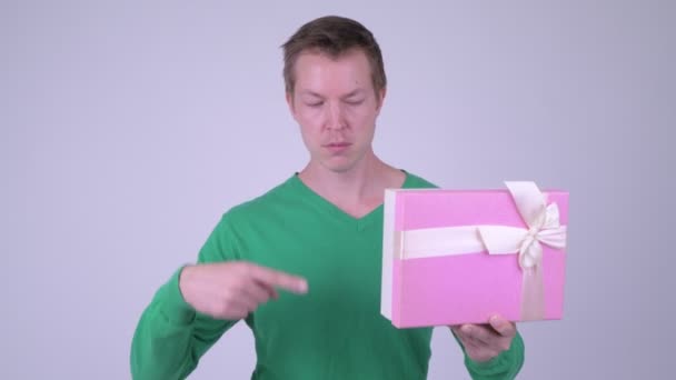 Счастливый молодой взволнованный мужчина дает большие пальцы вверх с подарочной коробке готов к Дню Святого Валентина — стоковое видео
