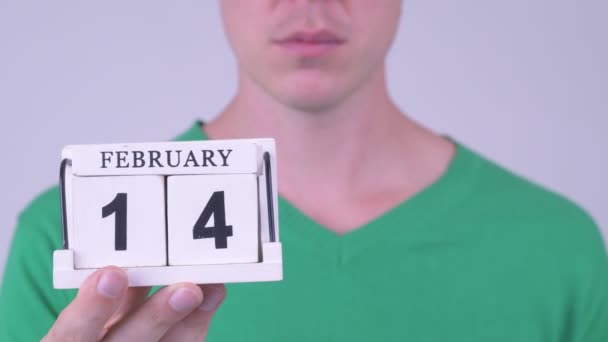 Happy young handsome man with calendar block and heart — Stock Video