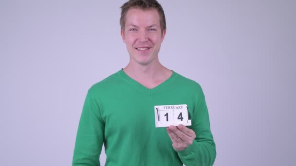 Happy young handsome man giving thumbs up with calendar block — Stock Video