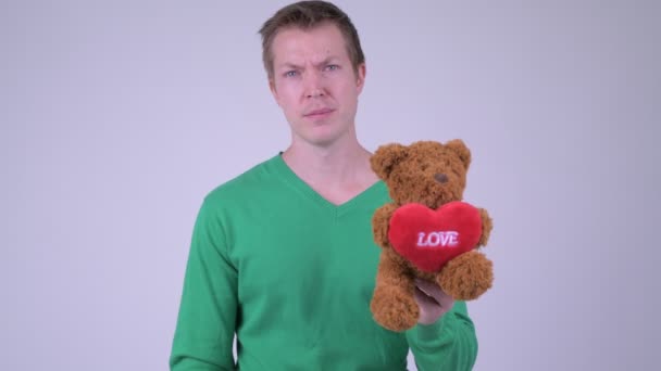 Porträt eines gestressten jungen Mannes, der mit Teddybär Daumen nach unten drückt — Stockvideo