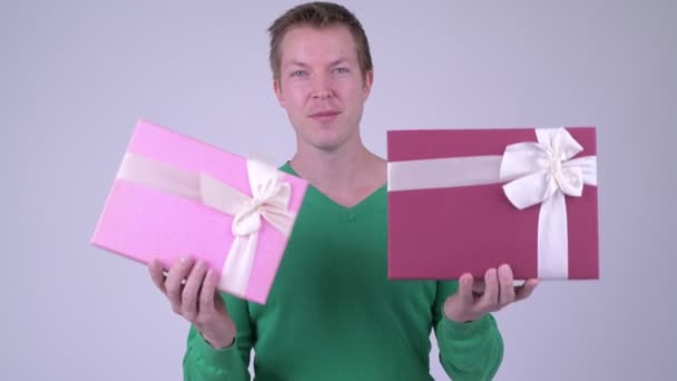 Счастливый молодой красивый мужчина с двумя подарочными коробками готов к Дню Святого Валентина — стоковое видео