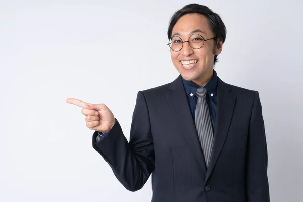 Retrato de feliz empresario japonés en traje apuntando hacia un lado —  Fotos de Stock