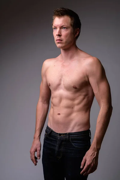 Studio shot of young handsome muscular shirtless man thinking — Stock Photo, Image