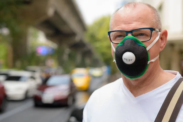 Senior man gezichtsmasker gebruiken om te beschermen tegen verontreiniging smog in de stad — Stockfoto