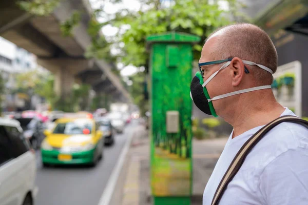 Senior man gezichtsmasker gebruiken om te beschermen tegen verontreiniging smog in de stad — Stockfoto