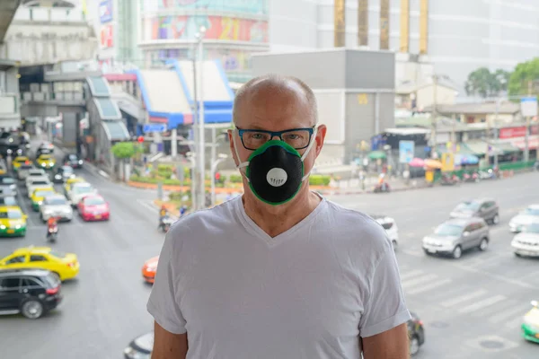 Senior man gezichtsmasker gebruiken om te beschermen tegen verontreiniging smog in de stad — Stockfoto