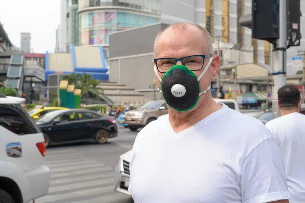 Senior man gezichtsmasker gebruiken om te beschermen tegen verontreiniging smog in de stad — Stockfoto