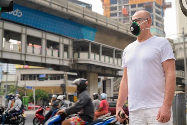 Senior man gezichtsmasker gebruiken om te beschermen tegen verontreiniging smog in de stad — Stockfoto