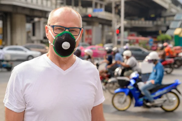 Senior man gezichtsmasker gebruiken om te beschermen tegen verontreiniging smog in de stad — Stockfoto