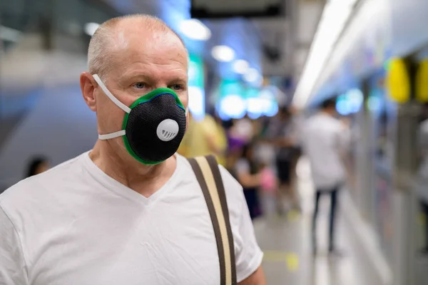Senior férfi álarc segítségével megvédeni a szennyezés szmog városában — Stock Fotó