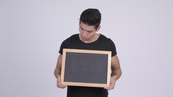 Junger glücklicher multiethnischer Mann denkt, während er die Tafel hält — Stockvideo