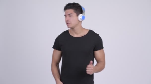 Молодой привлекательный многонациональный мужчина, слушающий музыку и выглядящий шокированным — стоковое видео