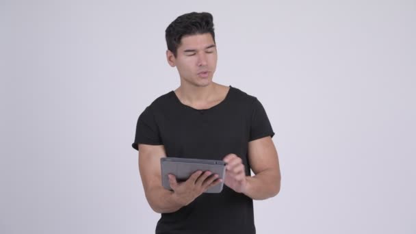 Szczęśliwy młody przystojny mężczyzna wieloetnicznego myślenia przy użyciu cyfrowego tabletu — Wideo stockowe