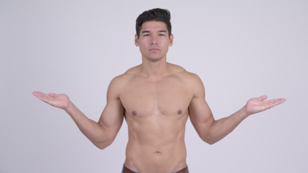 Glücklicher junger gutaussehender muskulöser Mann ohne Hemd, der etwas vergleicht — Stockvideo