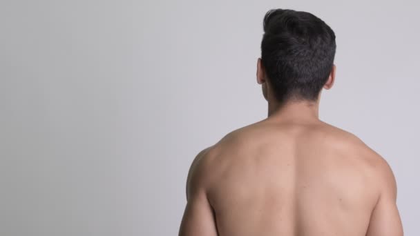 Задний вид молодого красивого мускулистого мужчины, оглядывающегося назад — стоковое видео