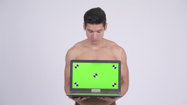Feliz joven sin camisa musculoso hombre mostrando el ordenador portátil y mirando sorprendido — Vídeos de Stock
