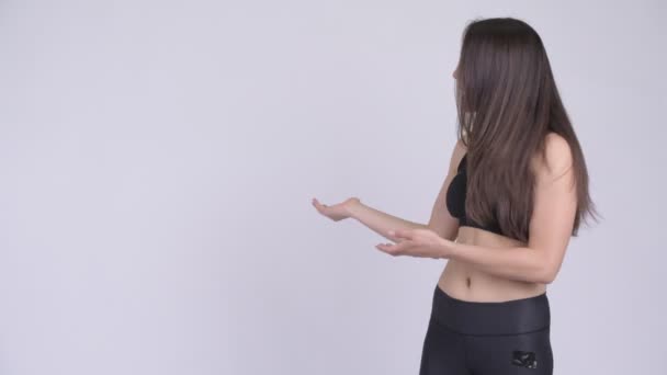 Junge glückliche multi-ethnische Frau zeigt etwas bereit für das Fitnessstudio — Stockvideo